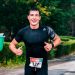 A fit male runner participating in an outdoor marathon during rainy conditions.